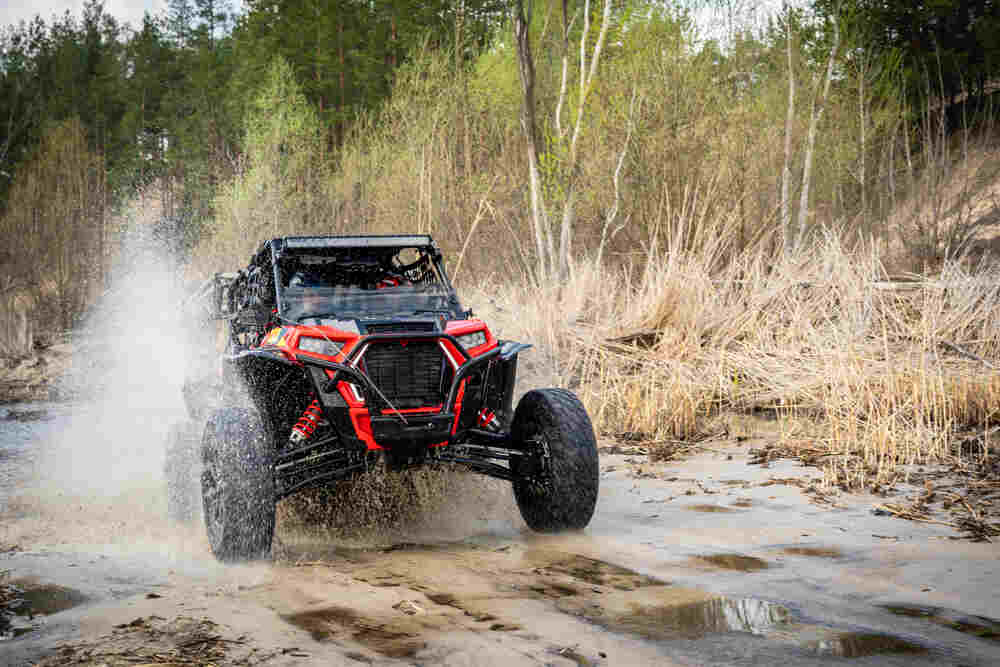 Red UTV driving through water